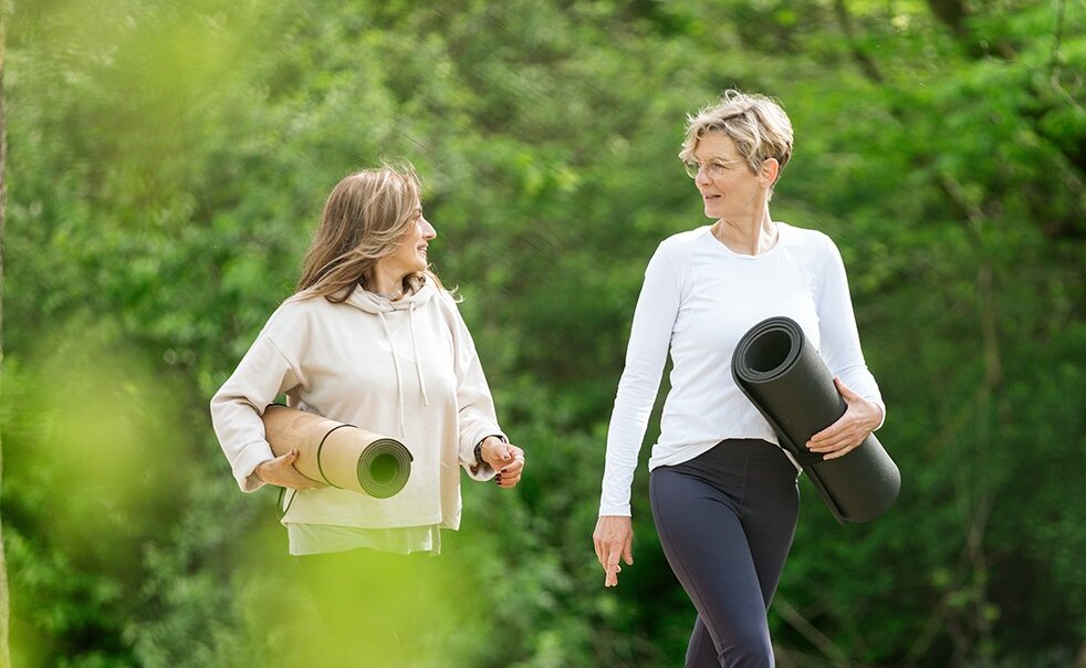 Zwei Frauen mit Yogamatte spazieren 