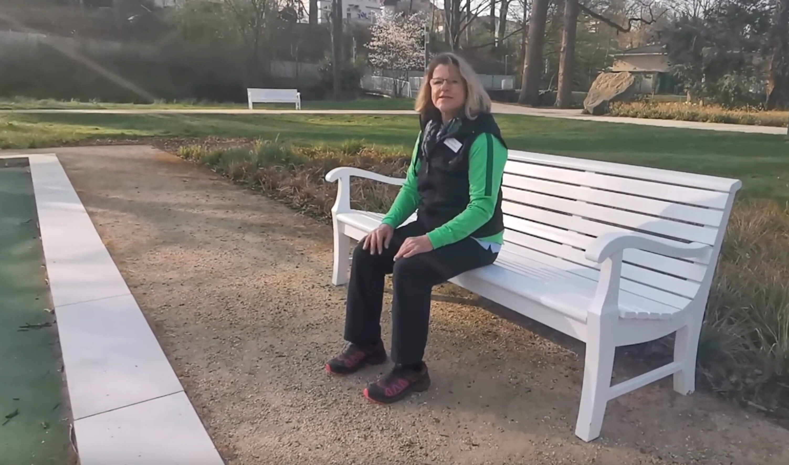Frau sitzt auf einer Bank im Park und erklärt Übungen